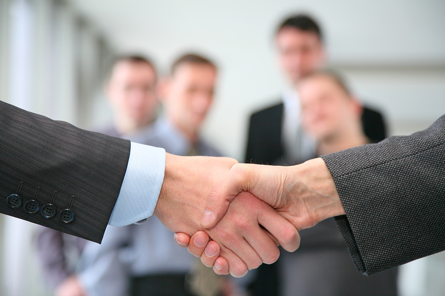 Corporate-Handshake-with-business-people-in-the-background1